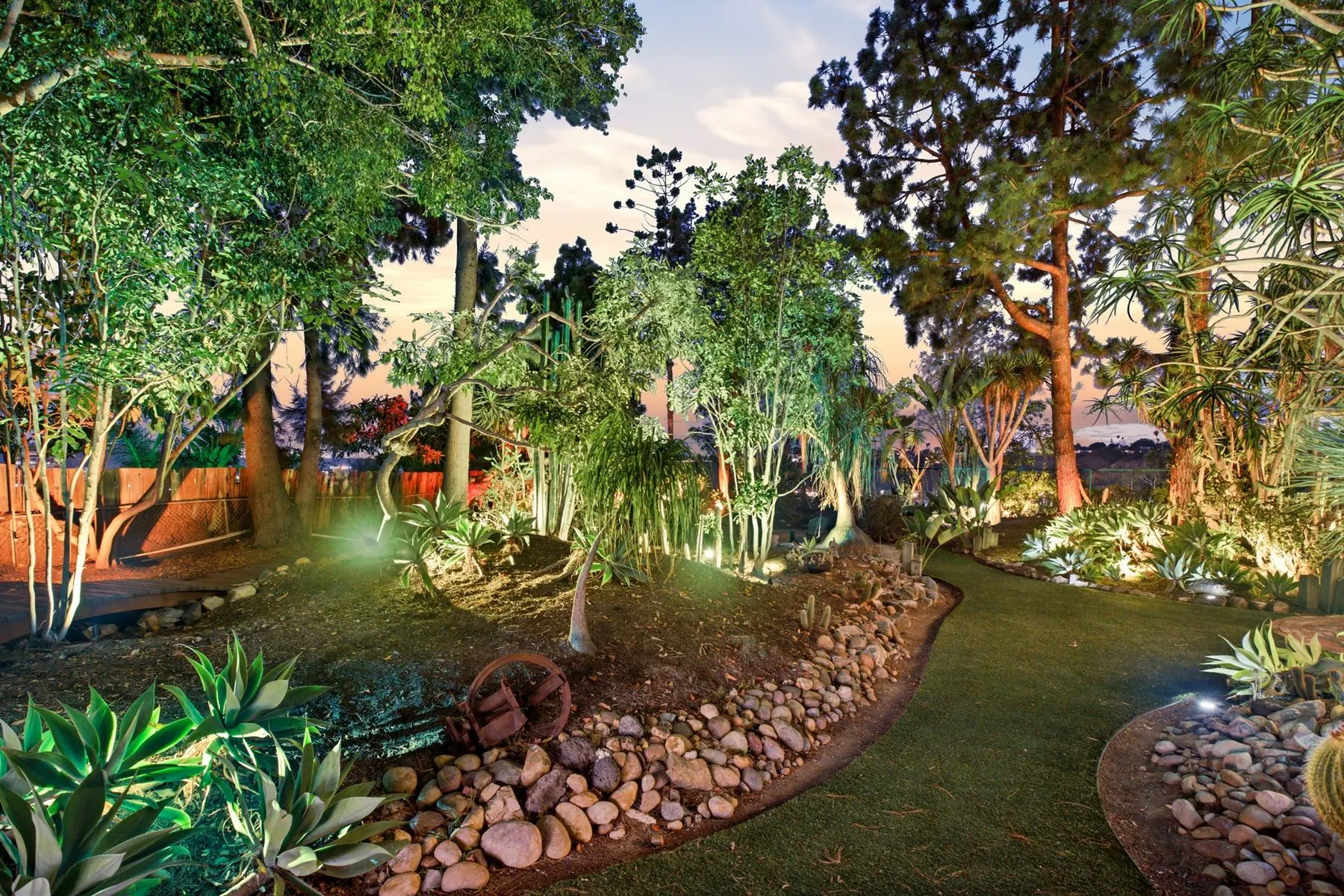 Winding lawn and river-rock beds, lit after dark