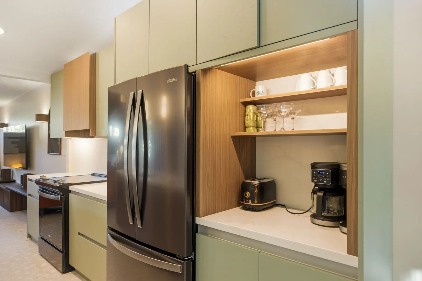 Built-in coffee station with walnut shelves beside the fridge